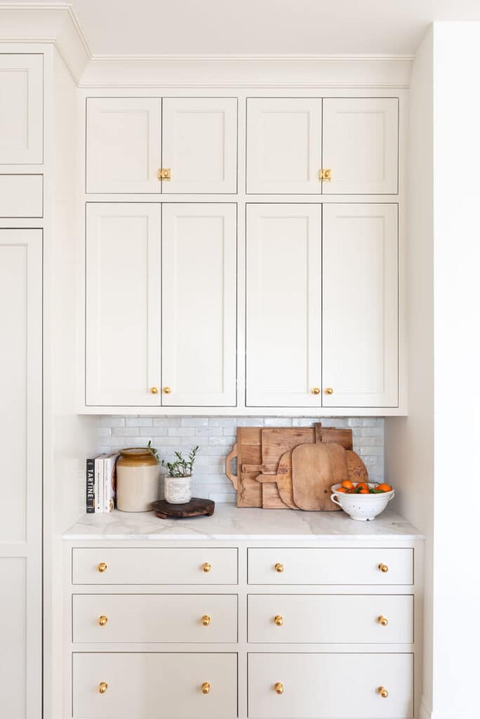 Beige cabinets that extend to the ceiling with trim and gold knobs