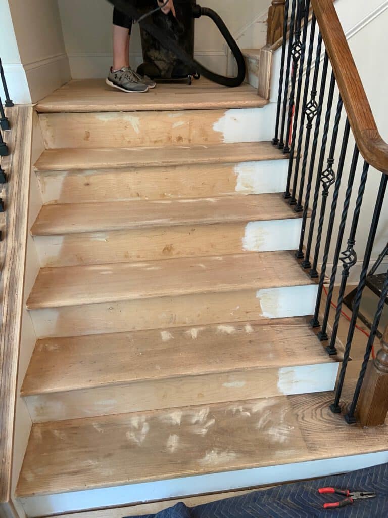 Sanded stair treads during refinishing with wood filler in holes 