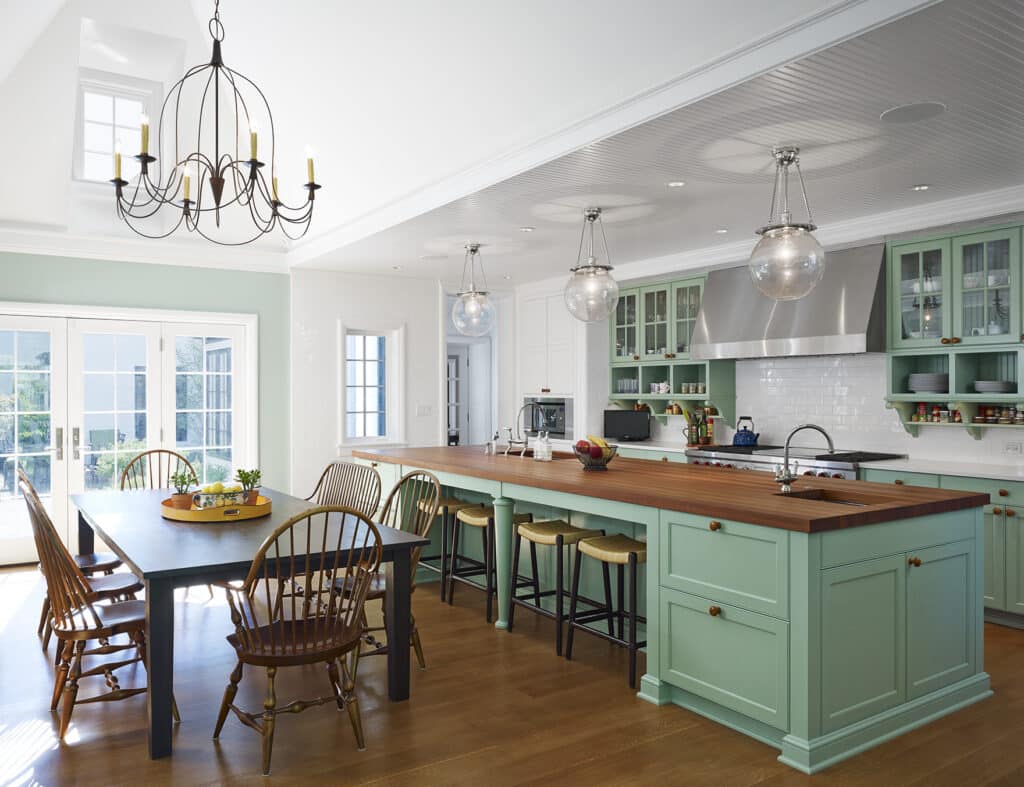 Light green kitchen island mixed with white cabinetry and wood countertops