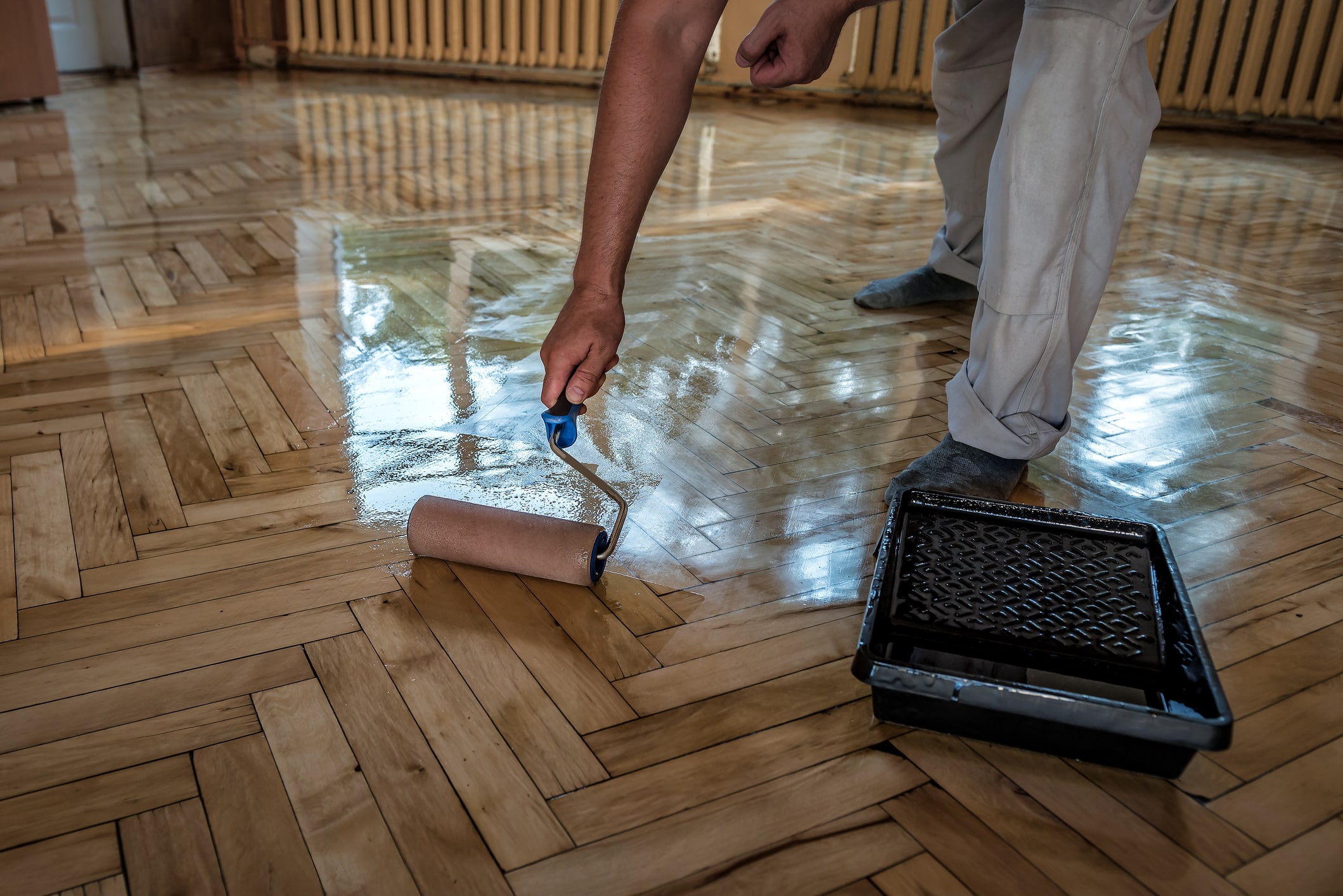 
Lacquering wood floors. Worker uses a roller to coating floors.