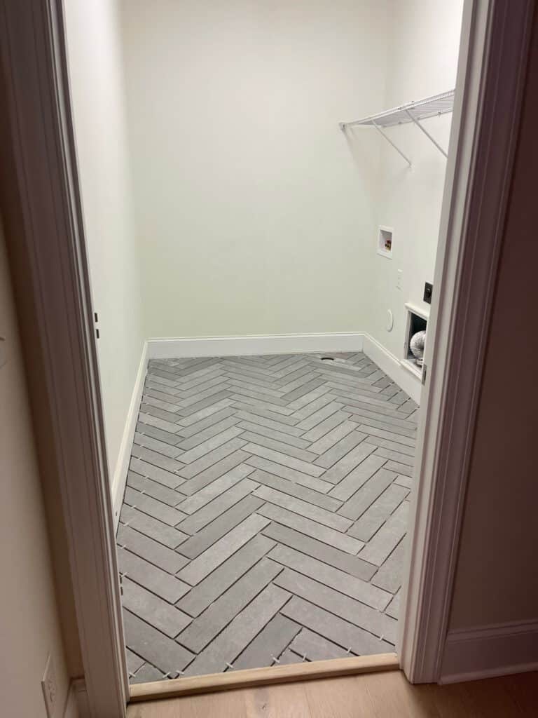 Grey Herringbone Tile Being Installed In A Laundry Room