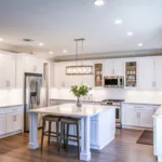 White painted oak cabinets in a farmhouse style kitchen with large island