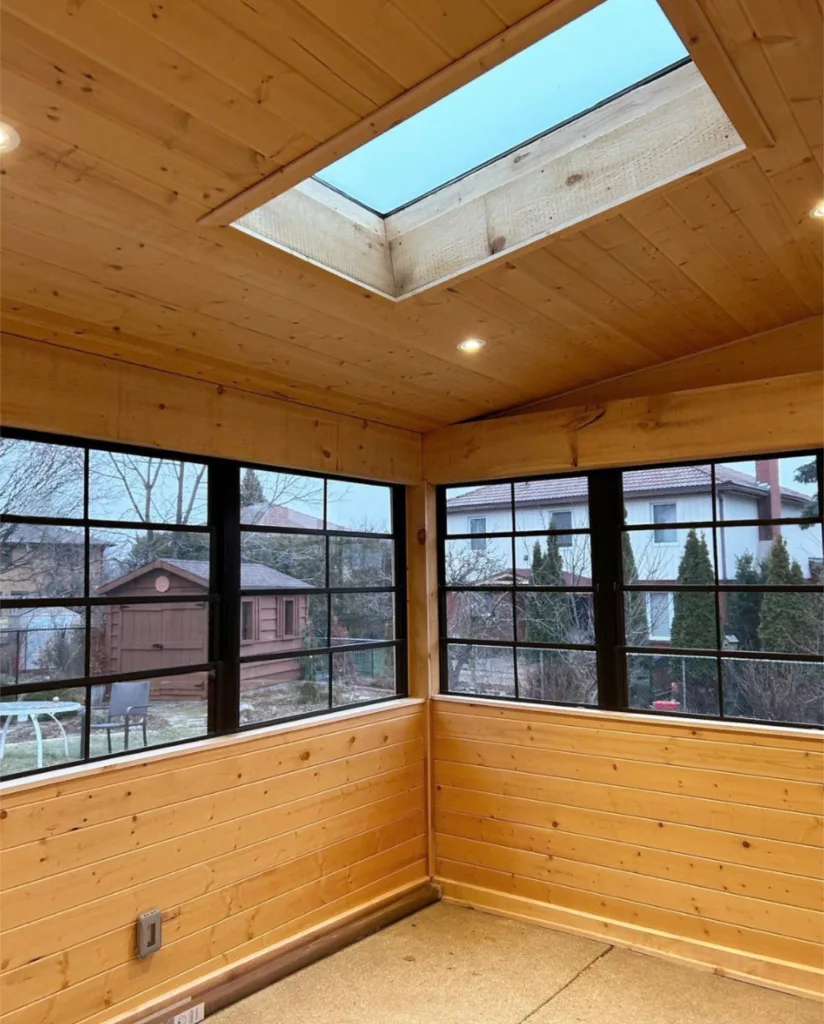 Wood paneled walls and sloped ceiling with black windows