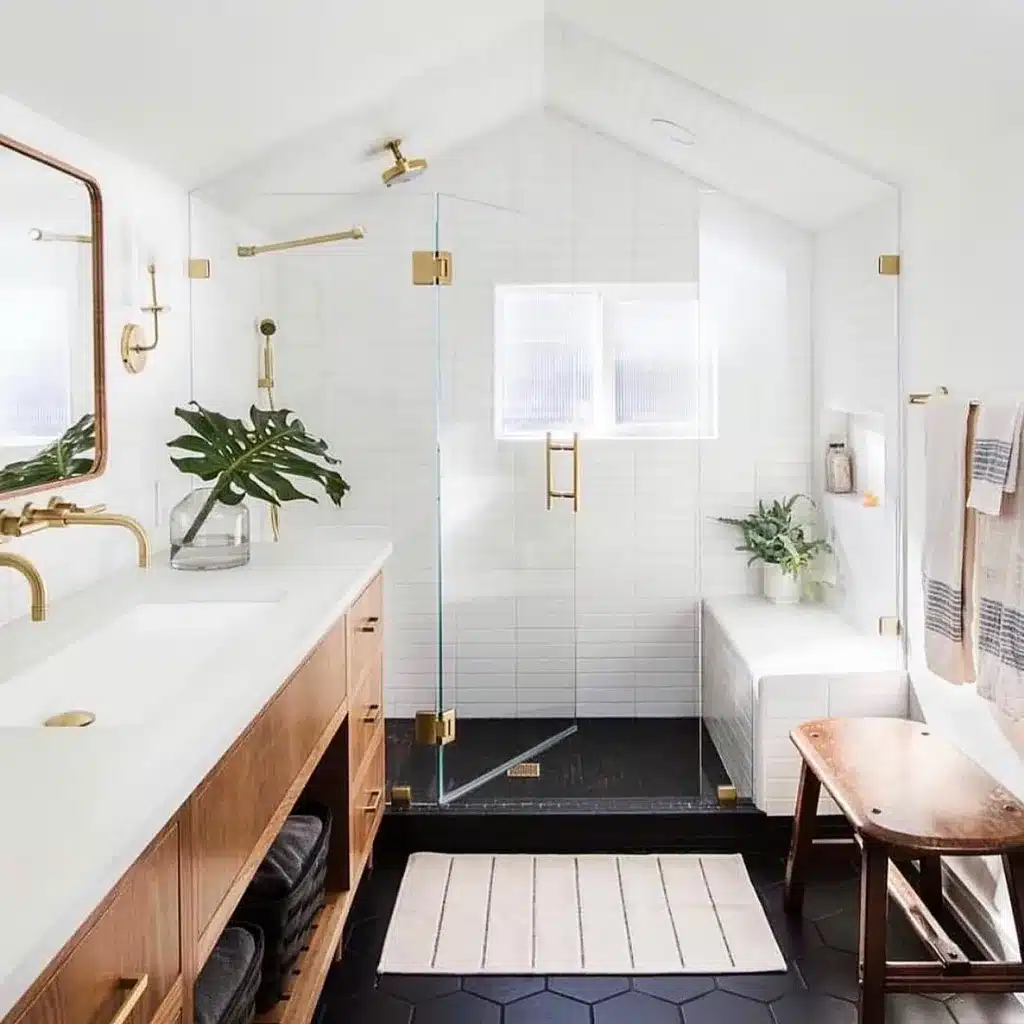 Black Floor And White Walls In A Bathroom With A Glass Shower And Gold Accents