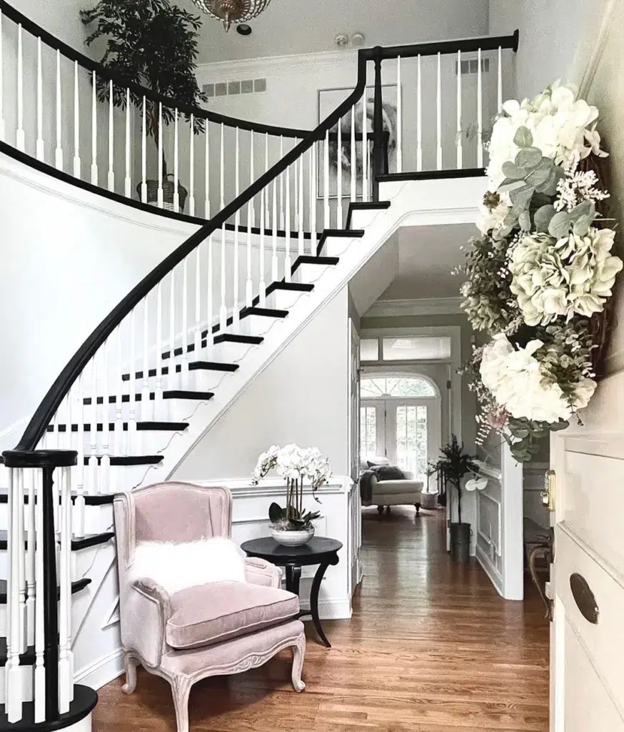 31 Black And White Stairs That Are Sure To Stun 24 White Railing With Black Handle With Black Steps. A Pink Accent Chair Is In Front Of The Stairs With Fur Pillows.