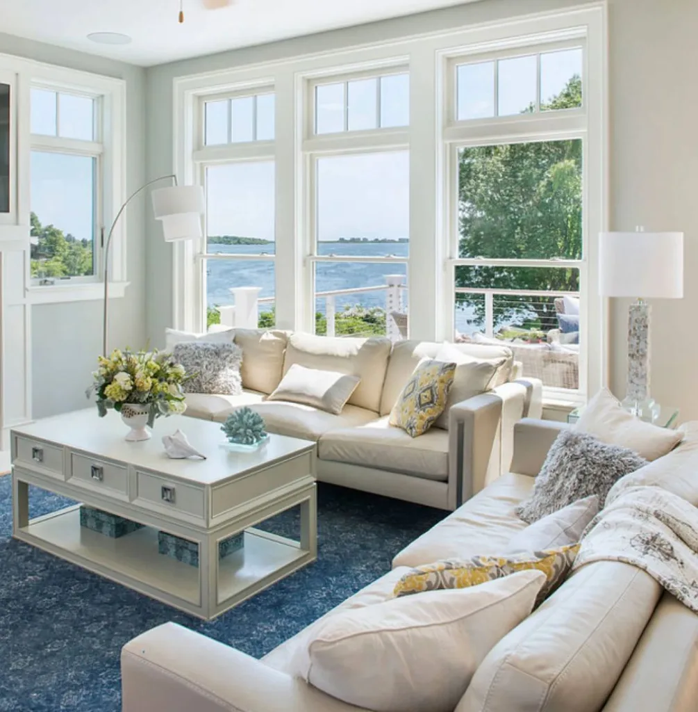31 Coastal Beach-Themed Living Room Ideas 9 Two Beige Couches On A Blue Rug In A Living Room Overlooking The Ocean