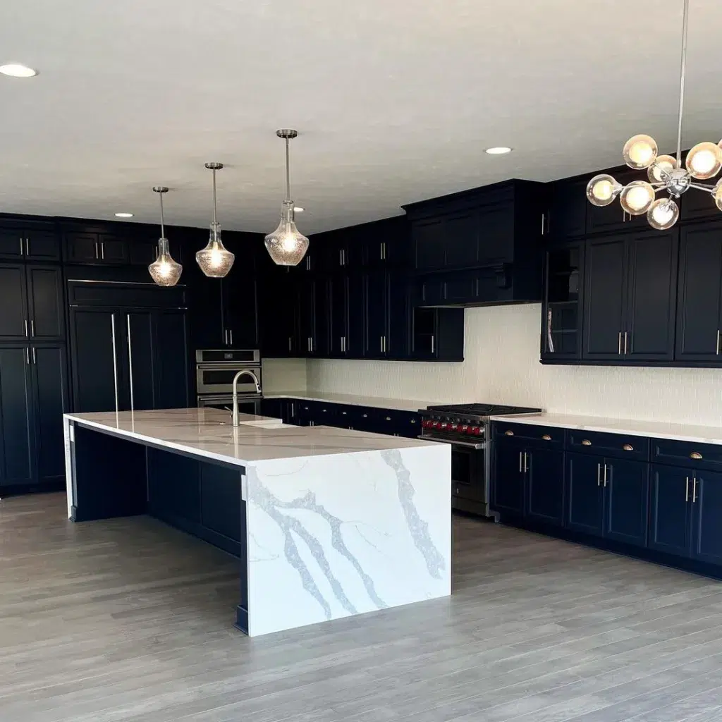 A Large Black Kitchen With A White And Grey Quartz Waterfall Island