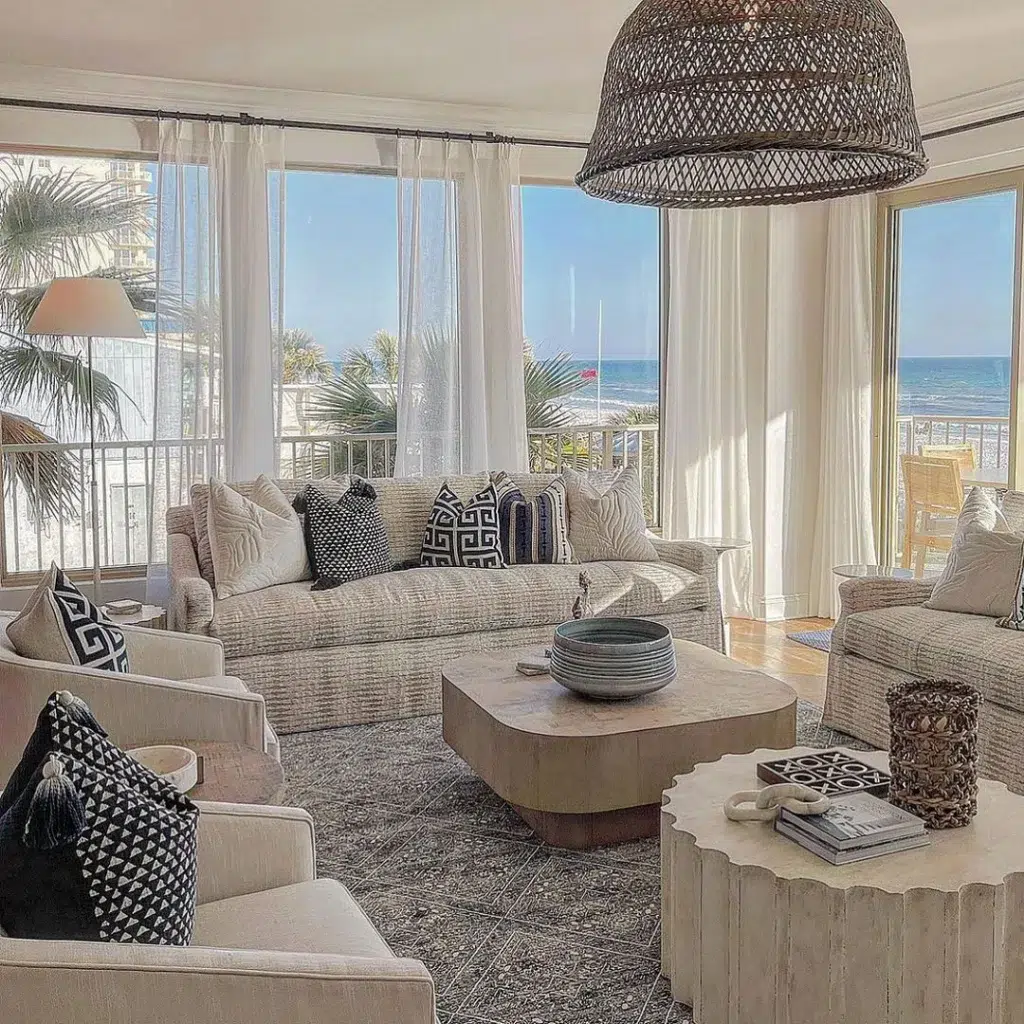 31 Coastal Beach-Themed Living Room Ideas 22 Beige Furniture In A Living Room With A Grey Rug Surrounded By Windows Overlooking The Ocean