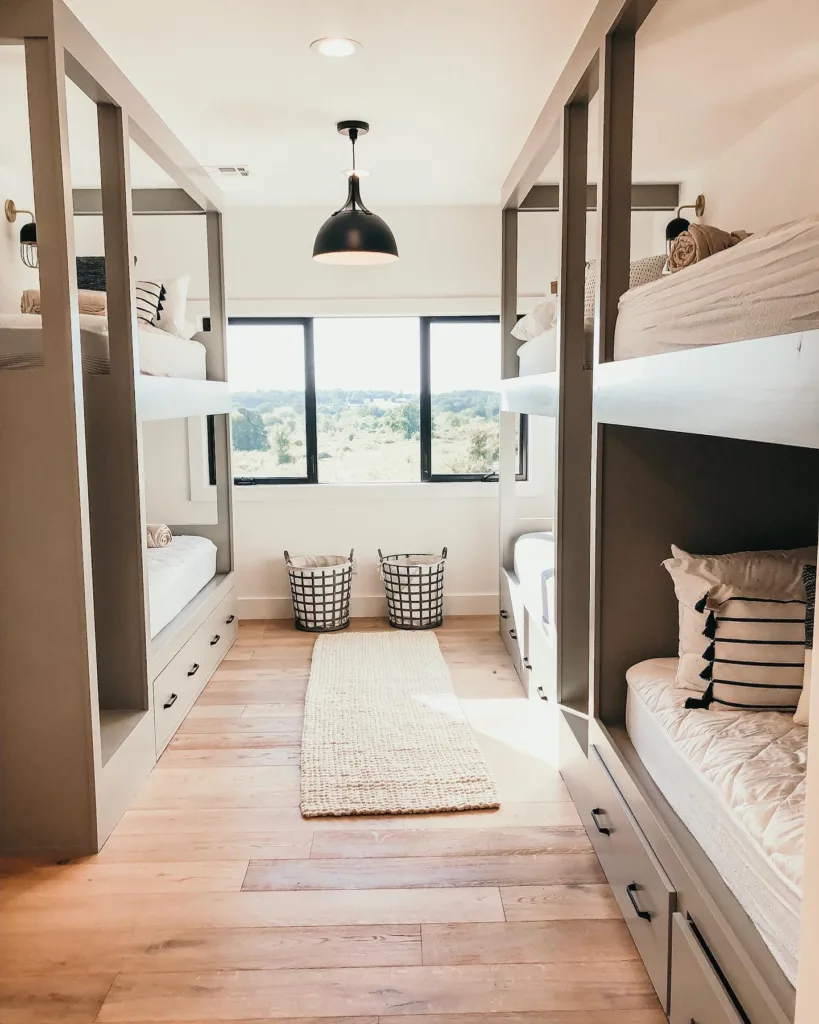 A Modern Bunk Room With White Oak Furniture And Two Large Windows With Black Framing