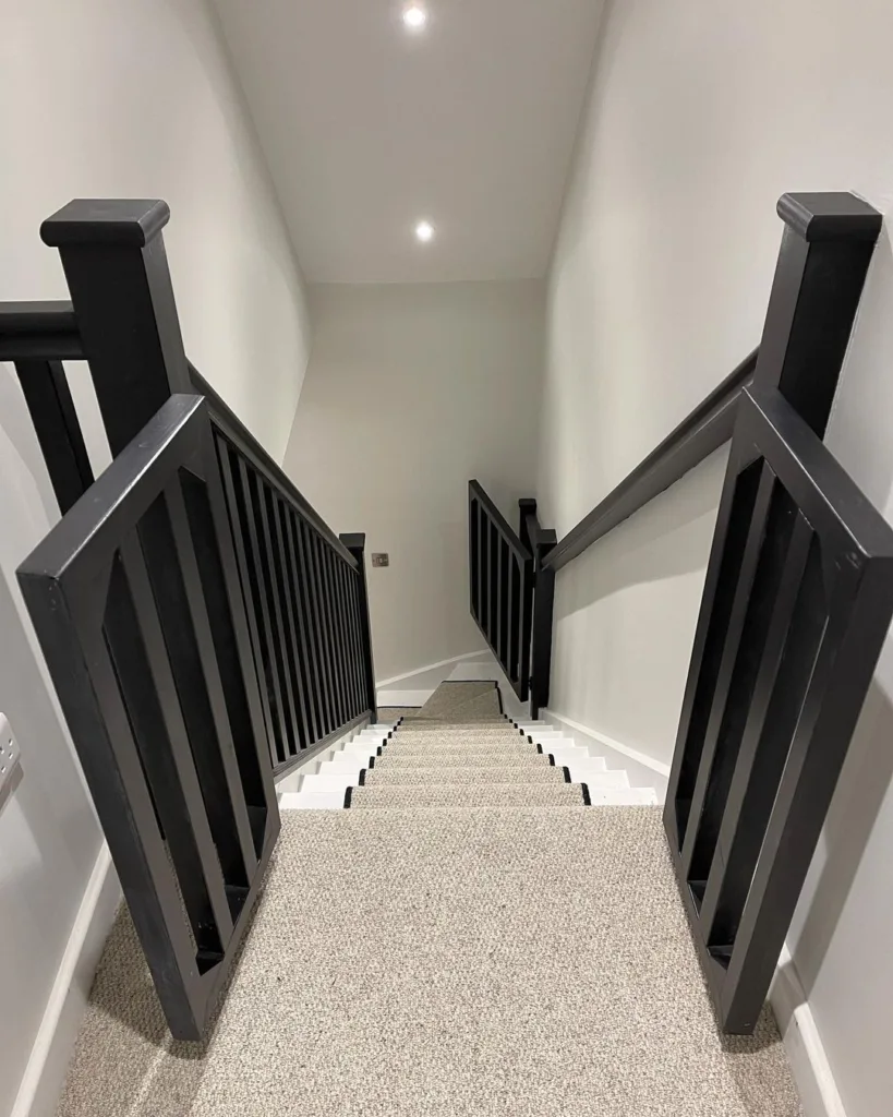 A White Staircase With Black Railings And A Grey Runner That Matches The Home'S Carpet