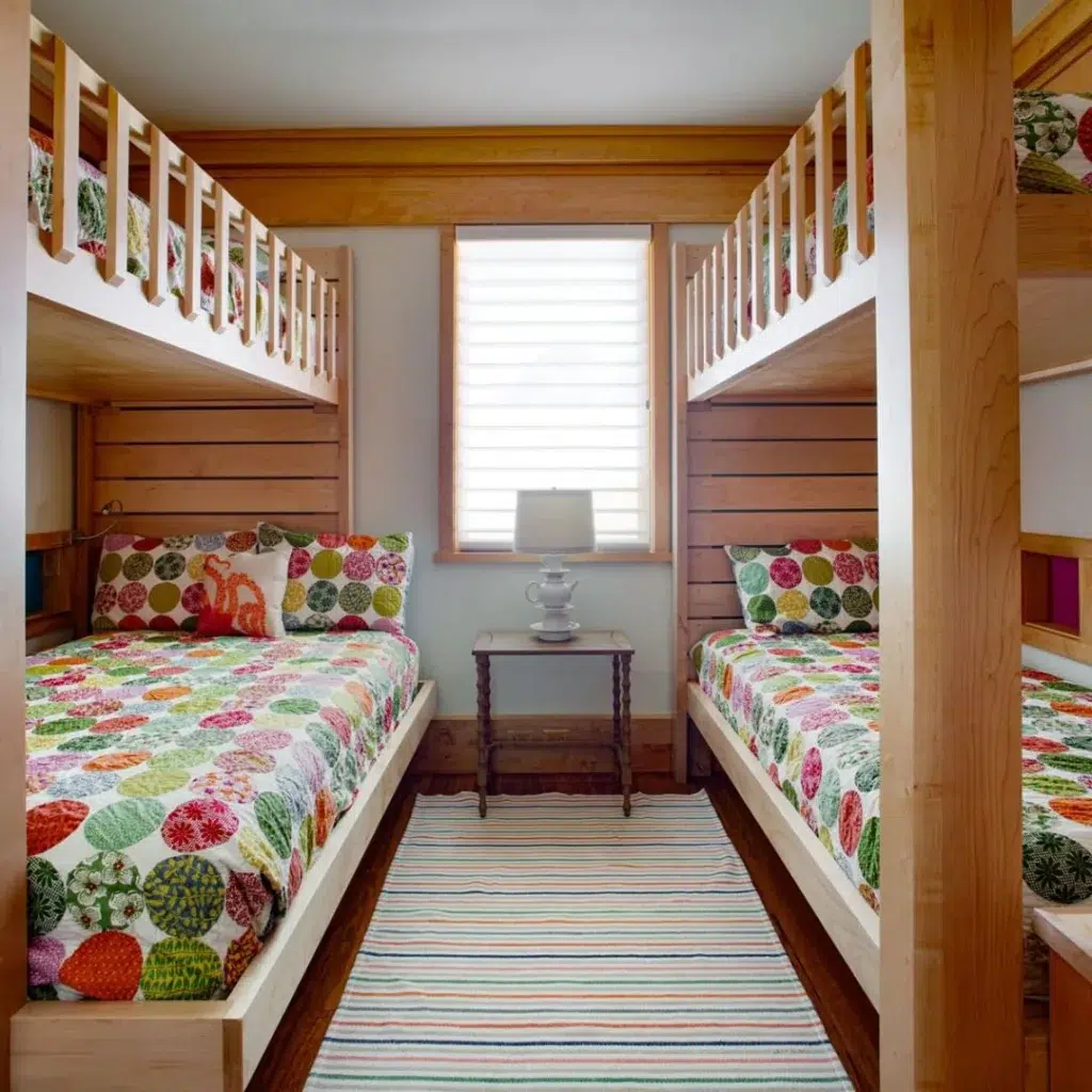 A Colorful Bunk Bed Room With Playful Bedding And Decor In A Wood Shiplap Cabin