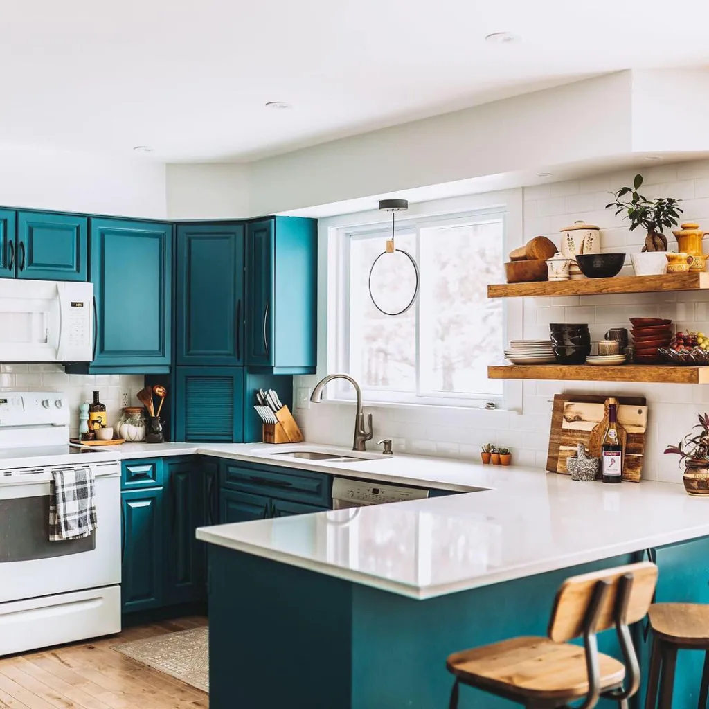 A Minimalist Teal Kitchen With A White Farmhouse Sink, Wooden Countertops, And Open Shelving For Displaying Dishes And Cookware.