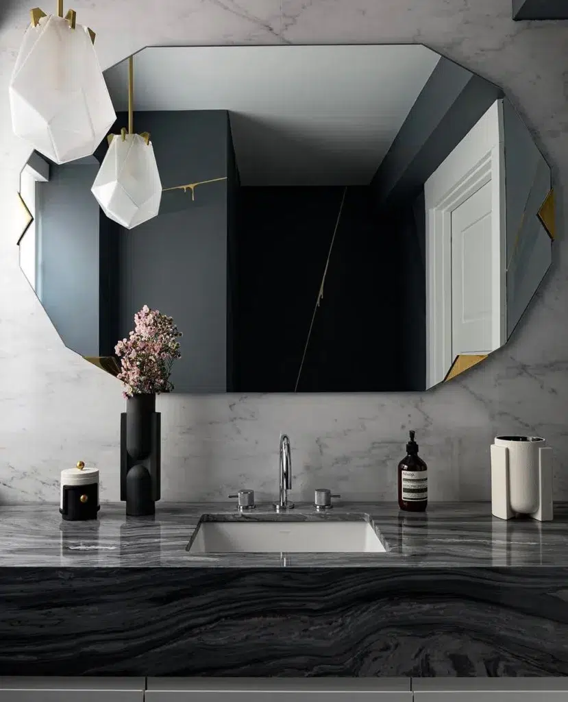 A Black Marble Vanity With A Matte Black Vase And Soap As Decor In Front Of The Mirror
