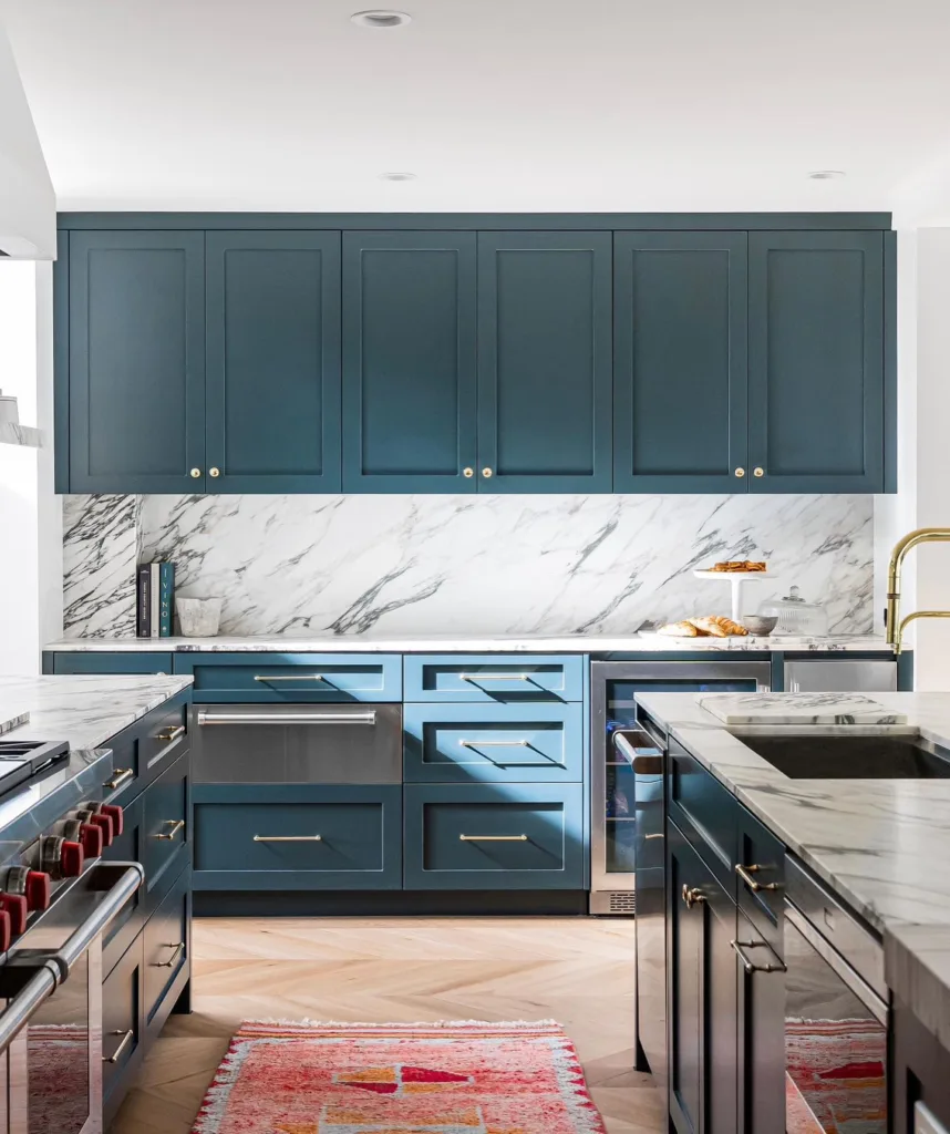 Marble Backsplash And Countertops With Teal Shaker-Style Cabinets With Brass Hardware