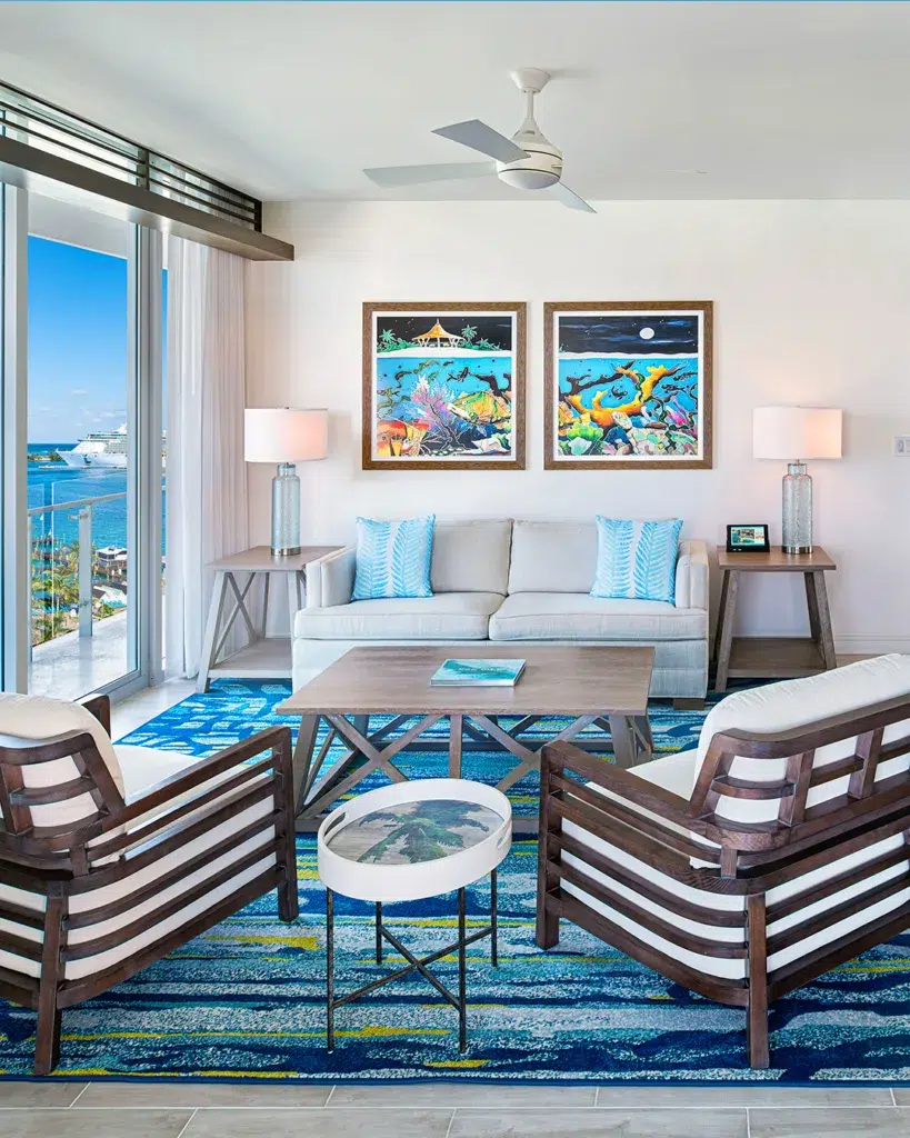 31 Coastal Beach-Themed Living Room Ideas 7 The Room Features A Comfortable White Sofa With Blue And White Striped Cushions, Surrounded By Natural Elements Such As Wicker Chairs, A Rattan Coffee Table, And A Jute Rug.
