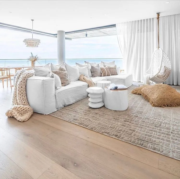 31 Coastal Beach-Themed Living Room Ideas 30 A Grey Plush Sofa And Ottomans With Large Open Sliding Windows Creating An Indoor Outdoor Space