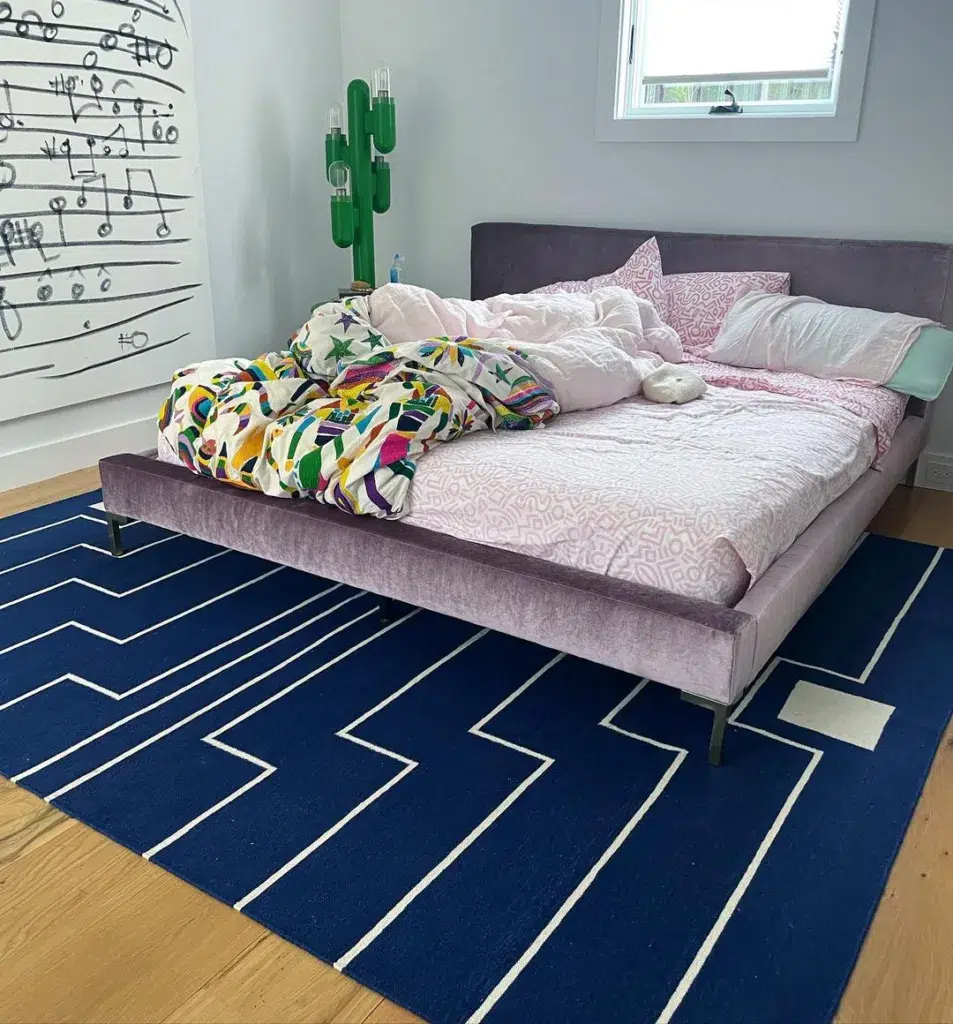 A Pink Bed On Top Of A Blue And White Striped Rug In A Kids Room