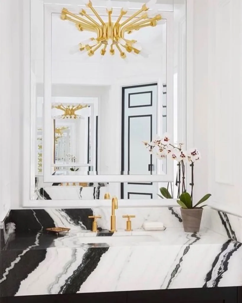 A Black And White Marble Vanity With A Plant As Decor For A Pop Of Color