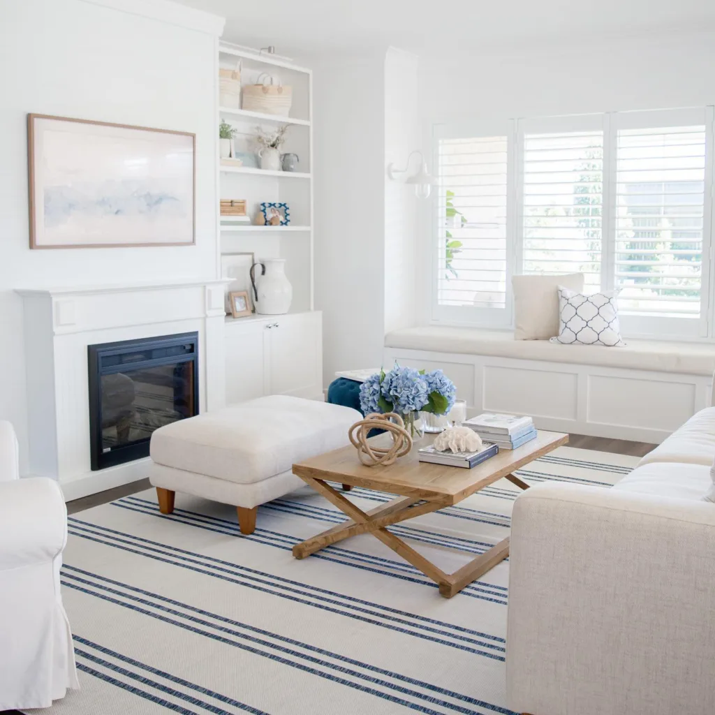 Light Grey Furniture And A Wood Coffee Table On A White And Blue Striped Rug In A Living Room