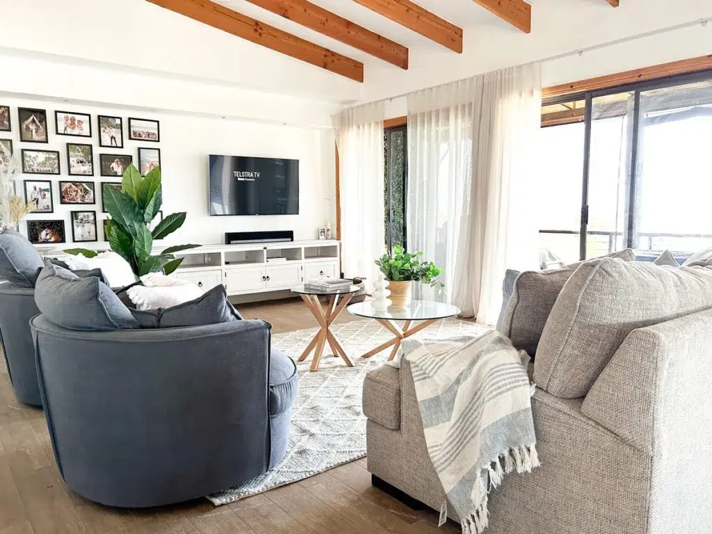 31 Coastal Beach-Themed Living Room Ideas 19 Brown Wood Ceiling Beams In A Living Room With Grey Accent Chairs And Sofa