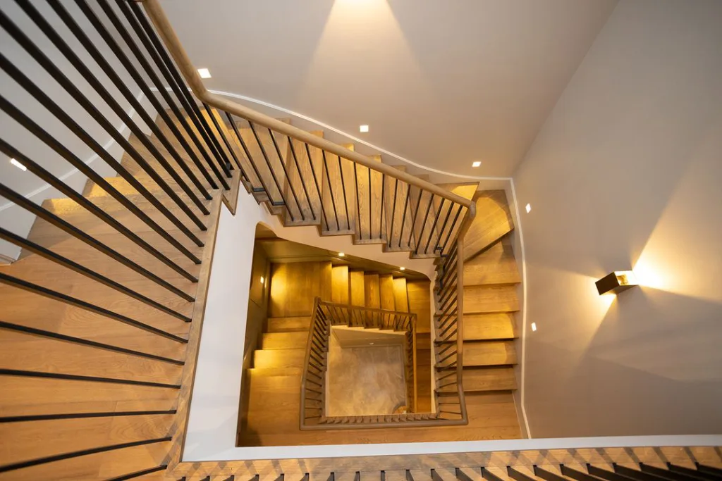 24 Curved Staircases For Design And Decor Inspiration 18 A Multi Floor Staircase Is Lit By A Stunning Chandelier Hanging From The Ceiling Above