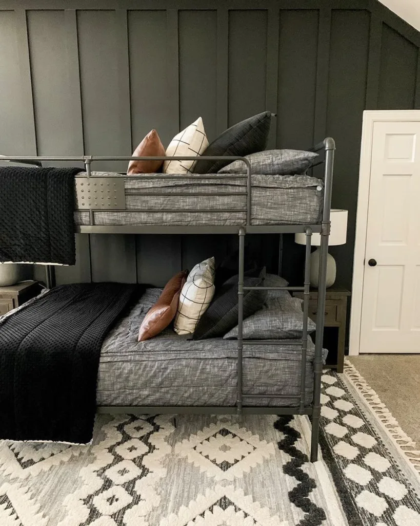 A Grey Wood Accent Wall Behind Two Bunk Beds With Metal Railings And Leather Accent Pillows