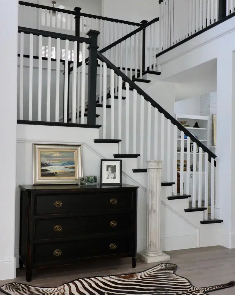 Black Treads And Railings On A Staircase With White Spindles To Match The White Walls In The Home