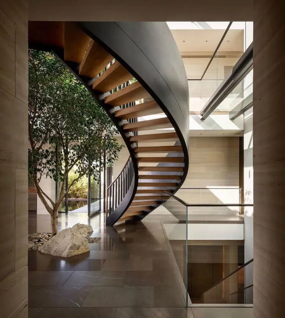 24 Curved Staircases For Design And Decor Inspiration 1 A View Of A Set Of Curved Stairs With Wooden Steps And Metal Railing, Leading Upwards To The Next Floor.