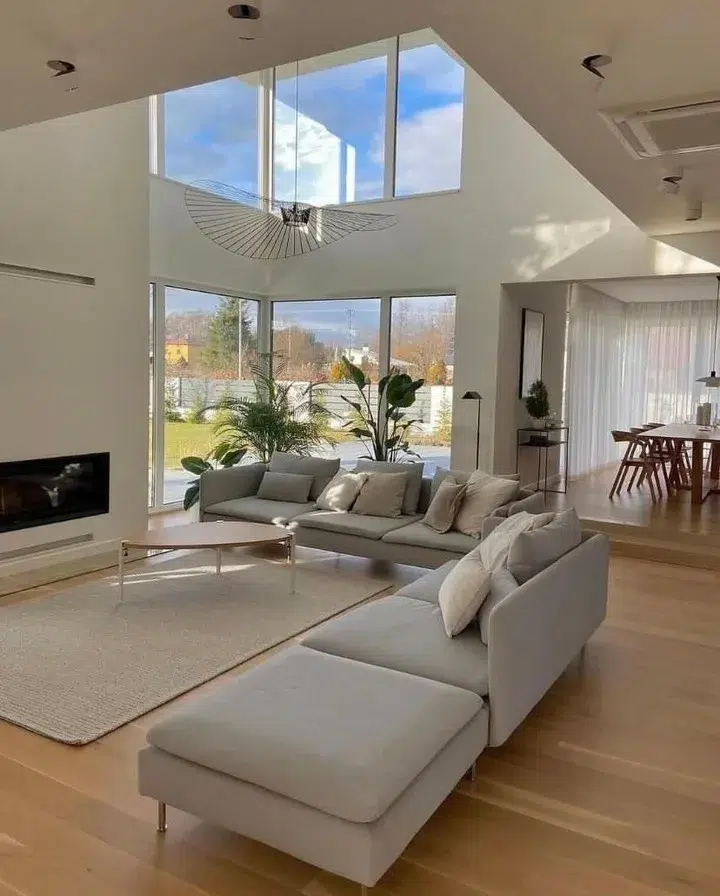 A Grey Sectional In A Modern Coastal Themed House With Two Story Windows