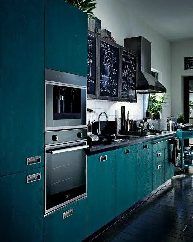 Black Appliances And Countertops In A Dark Teal Kitchen With Black Floors