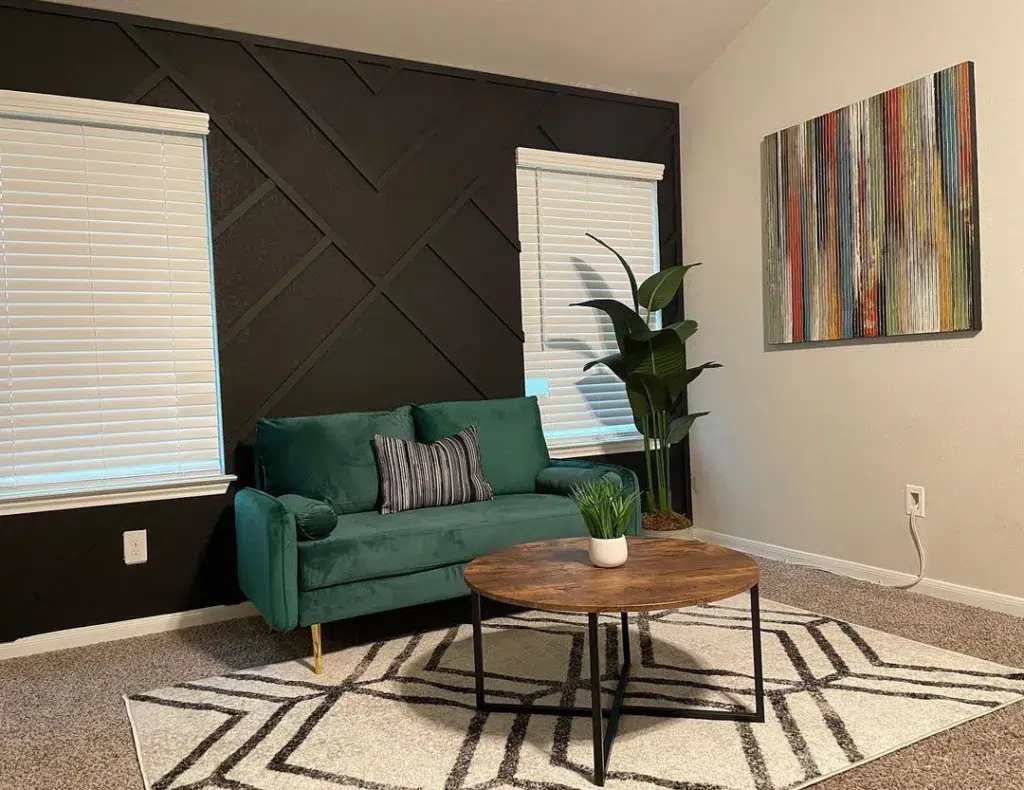 34 Black Accent Wall Ideas For Stunning Contrast 33 A Green Couch In Front Of A Black Wall With Angled Wood Trim