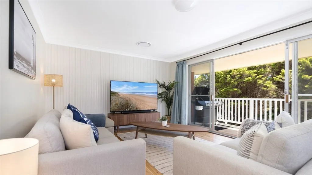 31 Coastal Beach-Themed Living Room Ideas 3 Two Grey Couches In A Coastal Apartment With Open Slider Doors That Lead To A Balcony