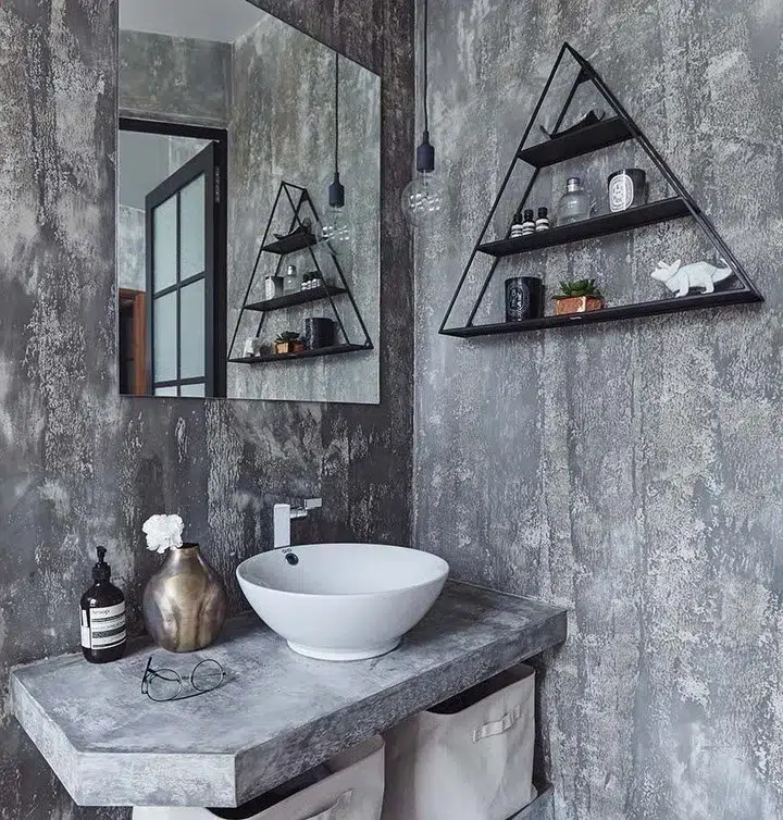 A Grey Cement Bathroom Vanity With A Gold Vase And Bottle Of Soap As Bathroom Decor