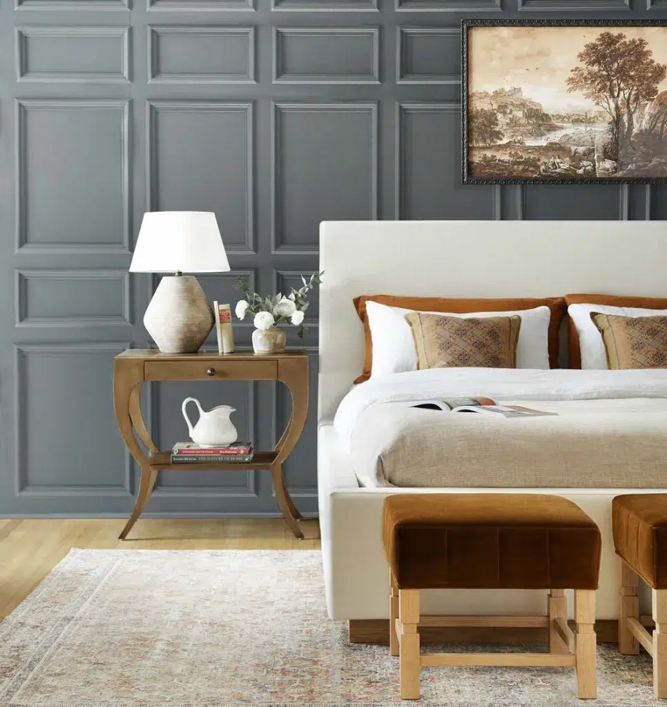 A Gray Molding Accent Wall Behind A Beige Bed On A Patterned Rug
