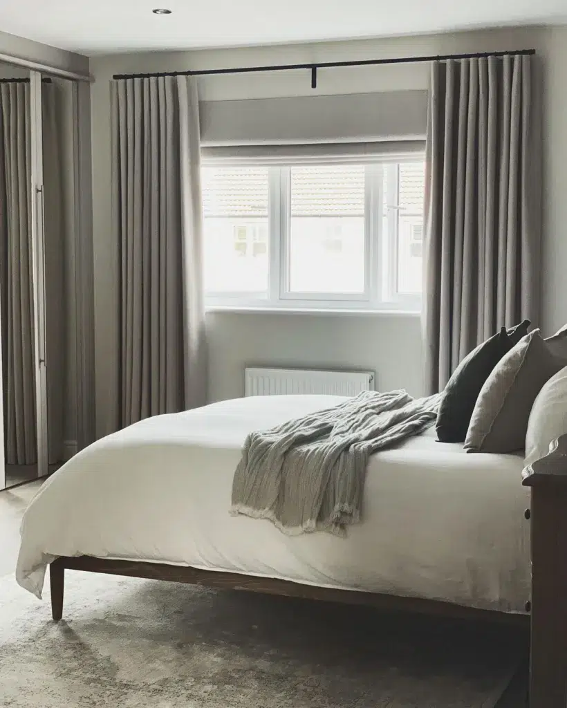 A Grey Bedroom With White Bedding And A Grey Rug