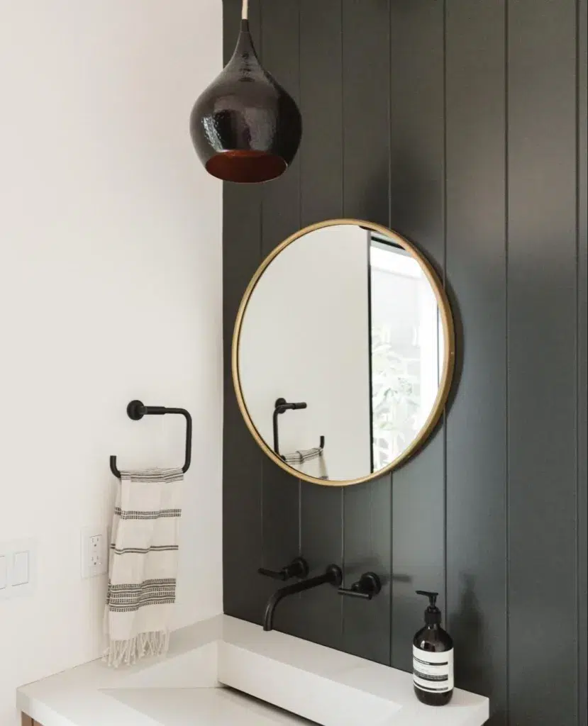 A Vertical Shiplap Accent Wall With A Gold Mirror In A Bathroom With A White Sink
