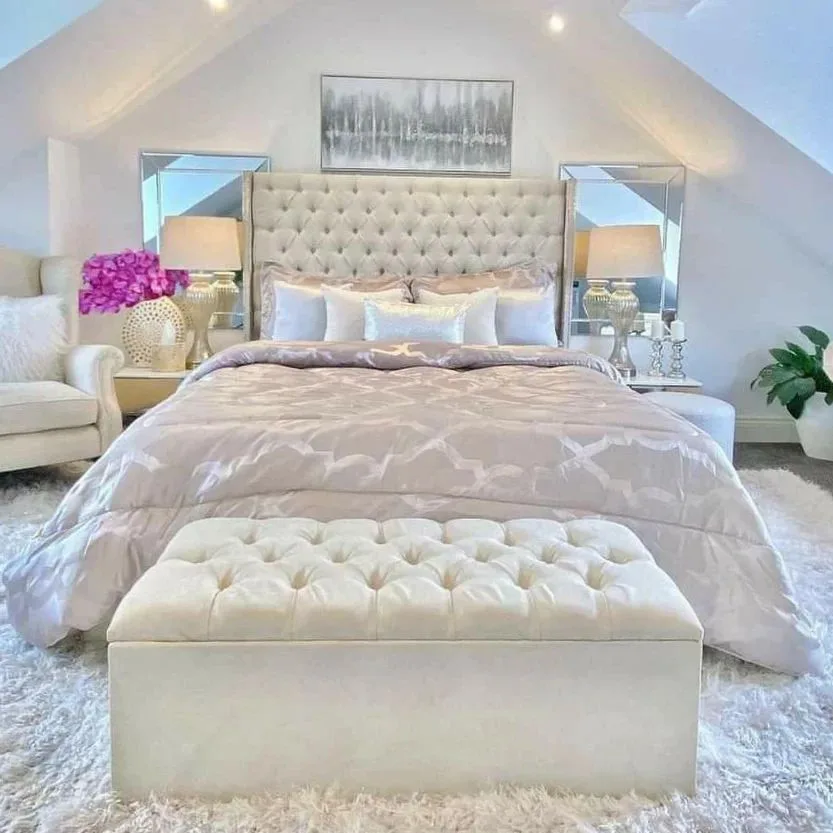 A Plush White Rug Under A Feminine Tufted Bed With A Matching Bench At The Foot Of The Bed
