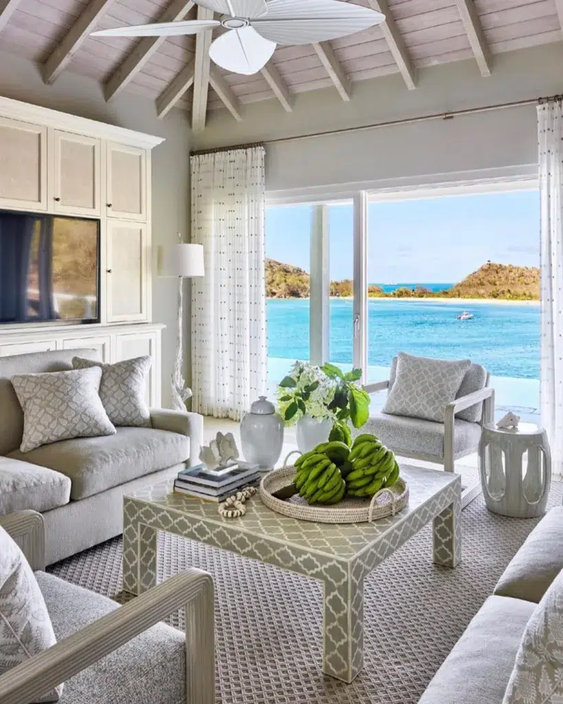31 Coastal Beach-Themed Living Room Ideas 26 White And Grey Furniture In A Sitting Area With Large Sliding Windows Overlooking Blue Ocean Water