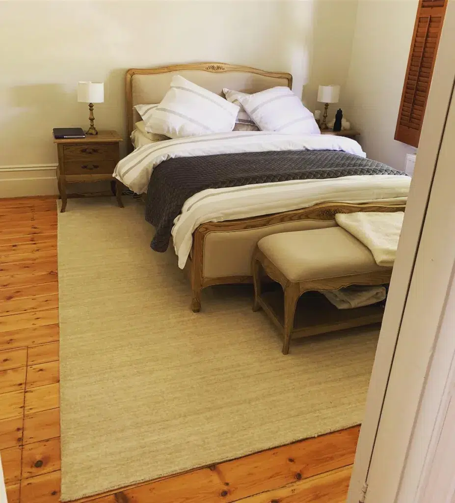 A Beige Rug Under A Beige Bed With Wood Accents