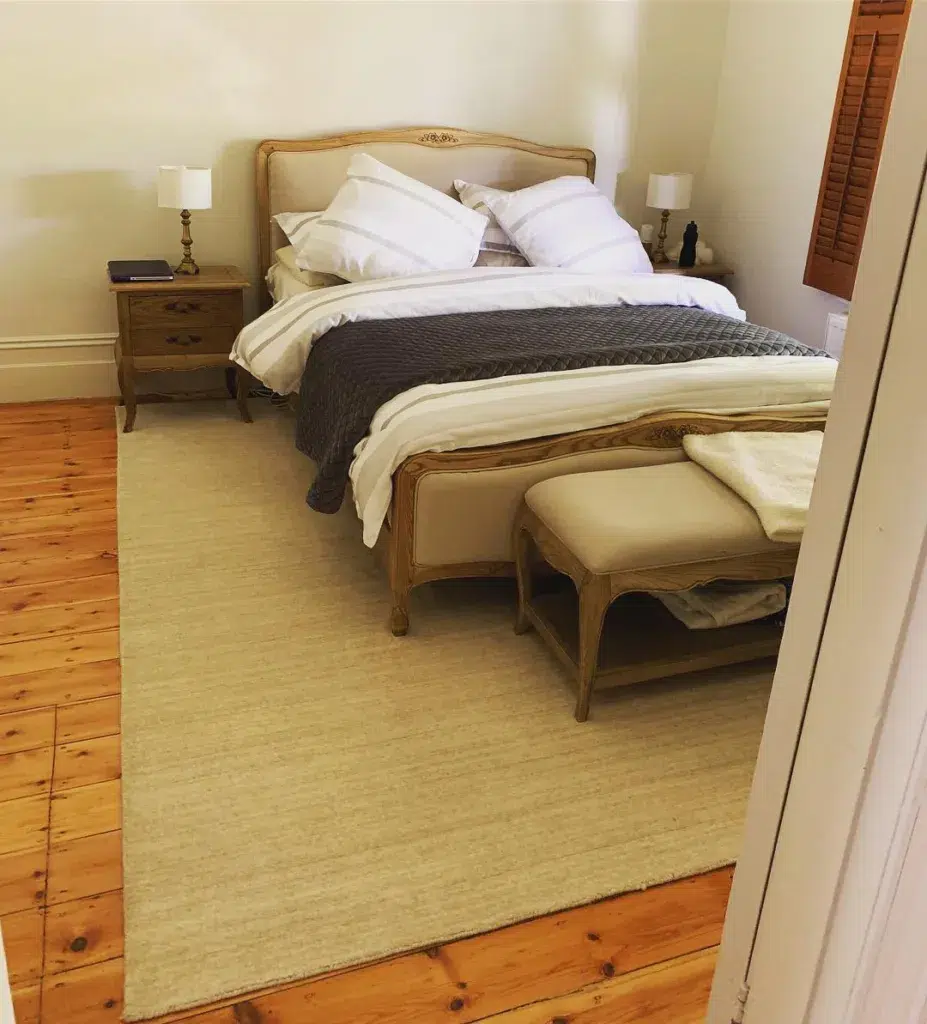 37 Rug Under Bed Ideas For A Stylish Bedroom 1 A Beige Rug Under A Beige Bed With Wood Accents