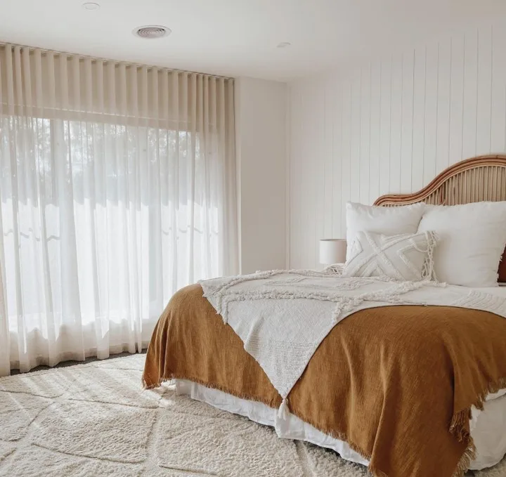 A Beige Rug With Texture Accenting The Orange And White Bedding On The Bed