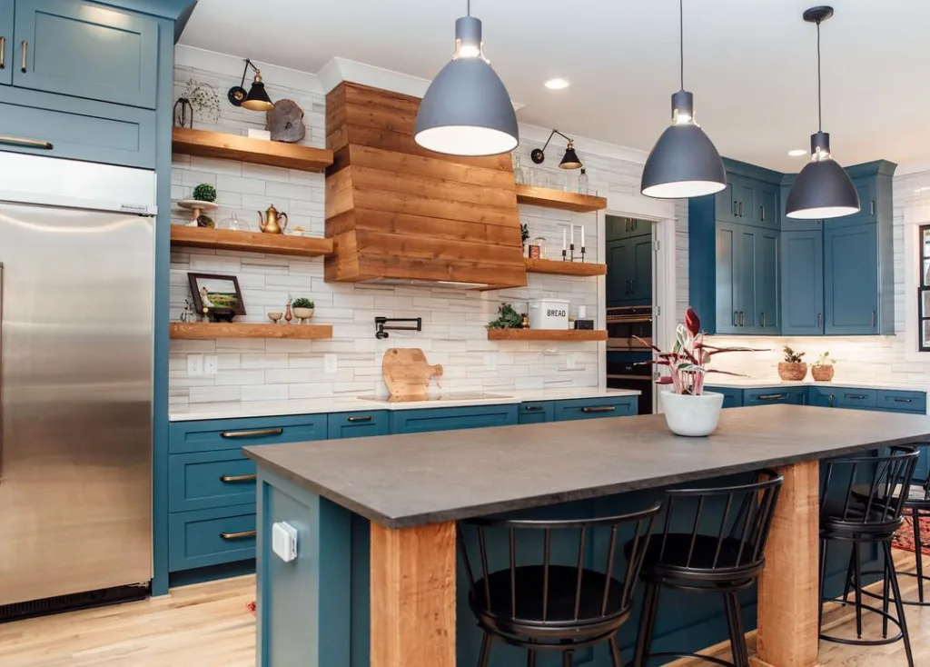 A Range Hood Covered In Wood Shiplap With Open Wood Shelves In A Teal Kitchen