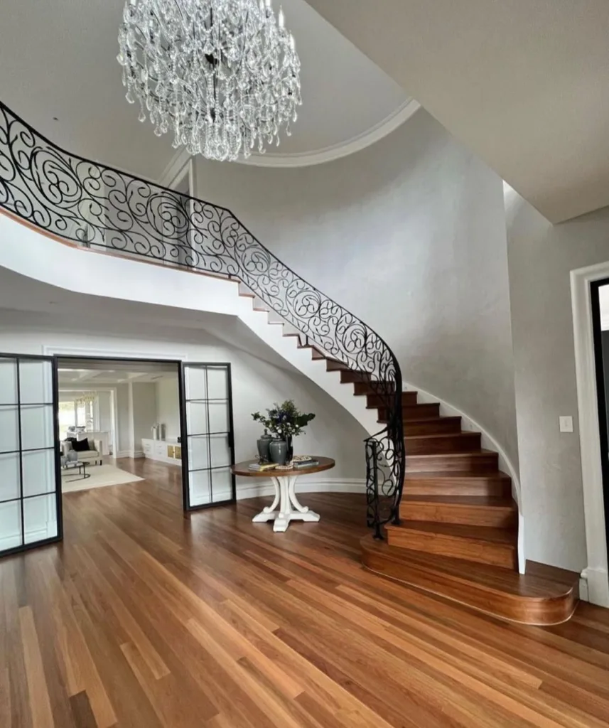 24 Curved Staircases For Design And Decor Inspiration 17 A Curved Staircase With Polished Wooden Steps, Iron Balusters And A Decorative Railing Leading Up To A Second Floor Landing