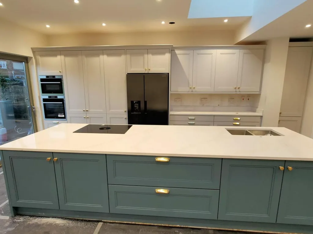 A Teal Kitchen Island With White Countertops And A Built-In Sink With White Cabinets In The Rest Of The Kitchen