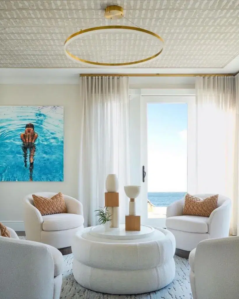 31 Coastal Beach-Themed Living Room Ideas 11 A Sitting Room With A View Of The Ocean And Four Beige Accent Chairs Arranged Around A Coffee Table