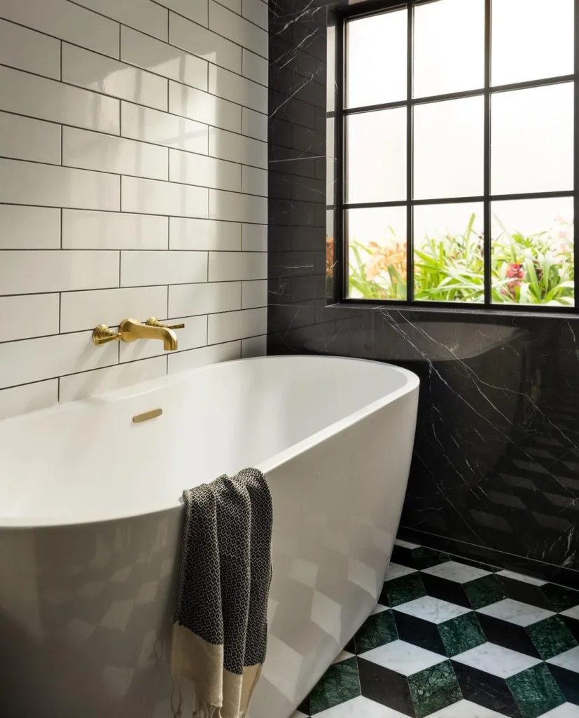 38 Bathrooms With Hexagon Tile Floors 22 A Sleek And Elegant Bathroom Featuring A Black, White, And Green Marble Hexagonal Tile Pattern On The Floor, Creating A Luxurious And Sophisticated Look. A White Tub Is The Centerpiece Of The Space, Providing A Comfortable And Relaxing Spot For Bathing. White Tiles Are Also Present On The Floor, Adding To The Clean And Minimalist Aesthetic. A Black-Framed Window Brings Natural Light Into The Space, Providing A Contrast To The Cool-Toned Marble Tiles.