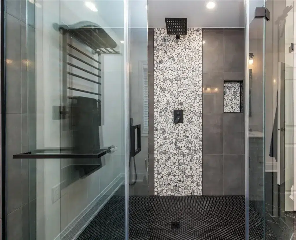 Black Small Hexagon Tiles On The Bathroom Floor With A Glass Partition For The Bathing Area. Dark Brown Tiles Are Used On The Bathroom Walls.