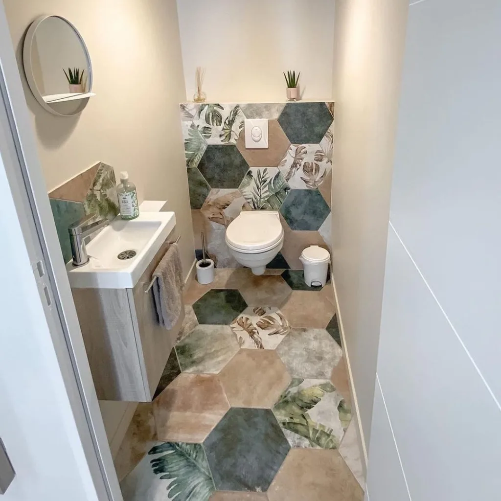 38 Bathrooms With Hexagon Tile Floors 21 A Fun And Vibrant Bathroom Featuring A Multi-Colored Hexagonal Tile Pattern On Both The Floor And The Walls, Creating A Playful And Energetic Atmosphere. A White Toilet Seat And Sink Are Located On The Left Side Of The Space, Providing A Clean And Neutral Contrast To The Colorful Tiles. The Hexagonal Tiles Have A Glossy Finish, Adding To The Cheerful And Lively Feel Of The Room.