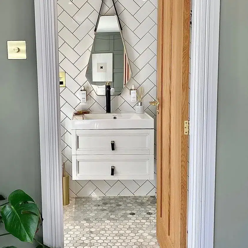 38 Bathrooms With Hexagon Tile Floors 28 &Quot;A Modern And Trendy Bathroom Featuring A Small Hexagonal Grey Tile Pattern On The Floor, Creating A Unique And Eye-Catching Look. A Triangle-Shaped Mirror Is Located On The Wall, Adding An Interesting Geometric Element To The Space. White Cupboards Are Located Below The Mirror, Providing Storage And Keeping The Overall Look Clean And Minimalist. White Tiles On The Walls Complement The Grey Floor, Creating A Cohesive And Stylish Design.
