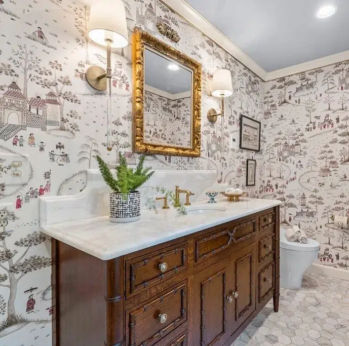 38 Bathrooms With Hexagon Tile Floors 24 A Cozy And Rustic Bathroom Featuring A Village-Inspired Wallpaper, Adding Warmth And Charm To The Space. Brown Wooden Cupboards Provide Ample Storage Space, While Also Adding To The Rustic Feel Of The Room. The Hexagonal Tile Pattern On The Floor Is A Subtle Shade Of Brown, Adding To The Earthy And Organic Atmosphere. A White Sink Is Located On The Right Side Of The Space, Providing A Clean And Neutral Contrast To The Wooden Cupboards. A Golden Mirror Adds A Touch Of Elegance And Refinement To The Space.